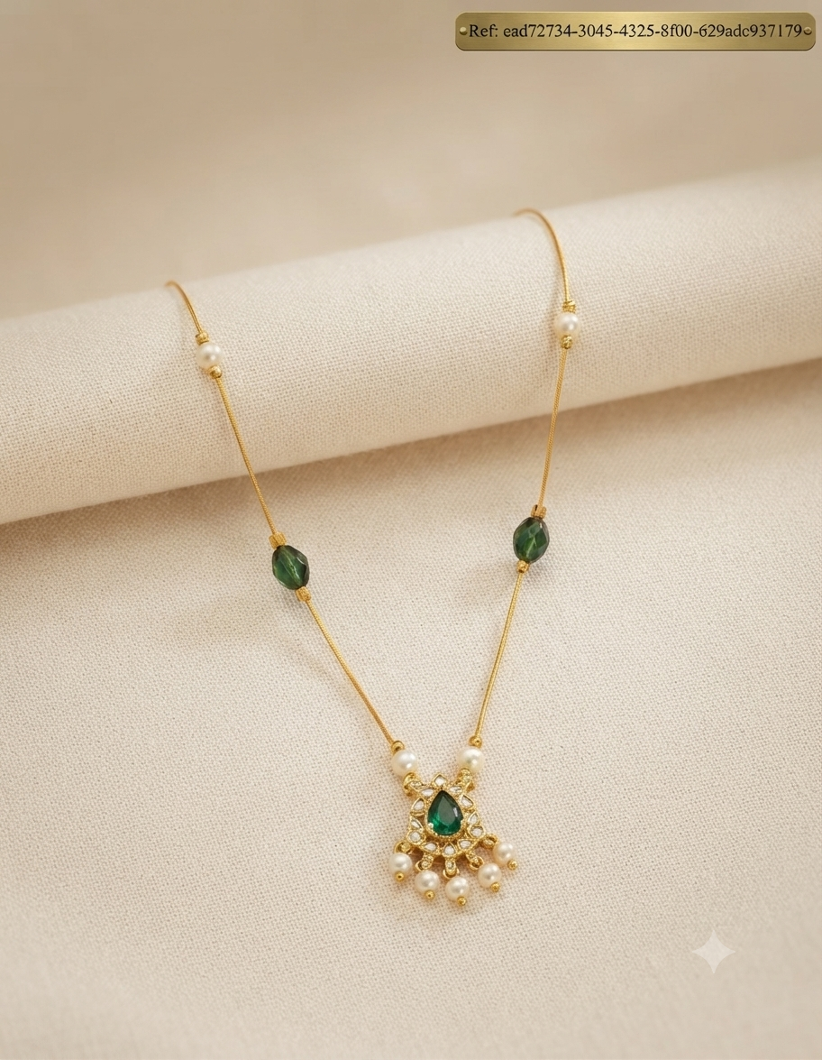 Invisible chain necklace with green stone pendant and pearl drops - flat lay on fabric